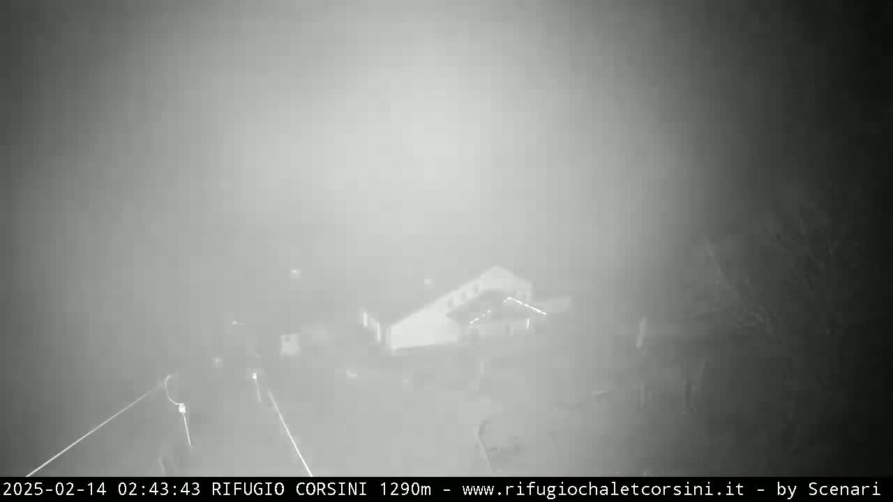 A blurry image shows a building in heavy fog at night.