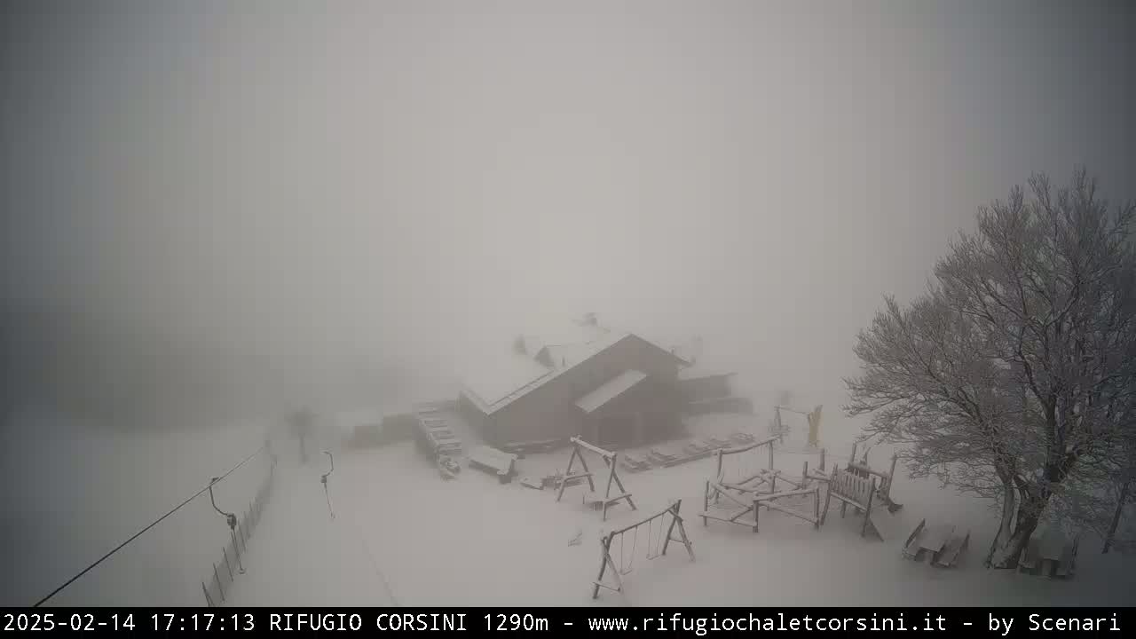 A snow-covered building with playground equipment is visible through heavy fog in a snowy landscape.