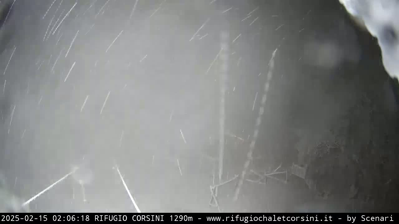 A blurry outdoor scene shows light snow falling heavily.