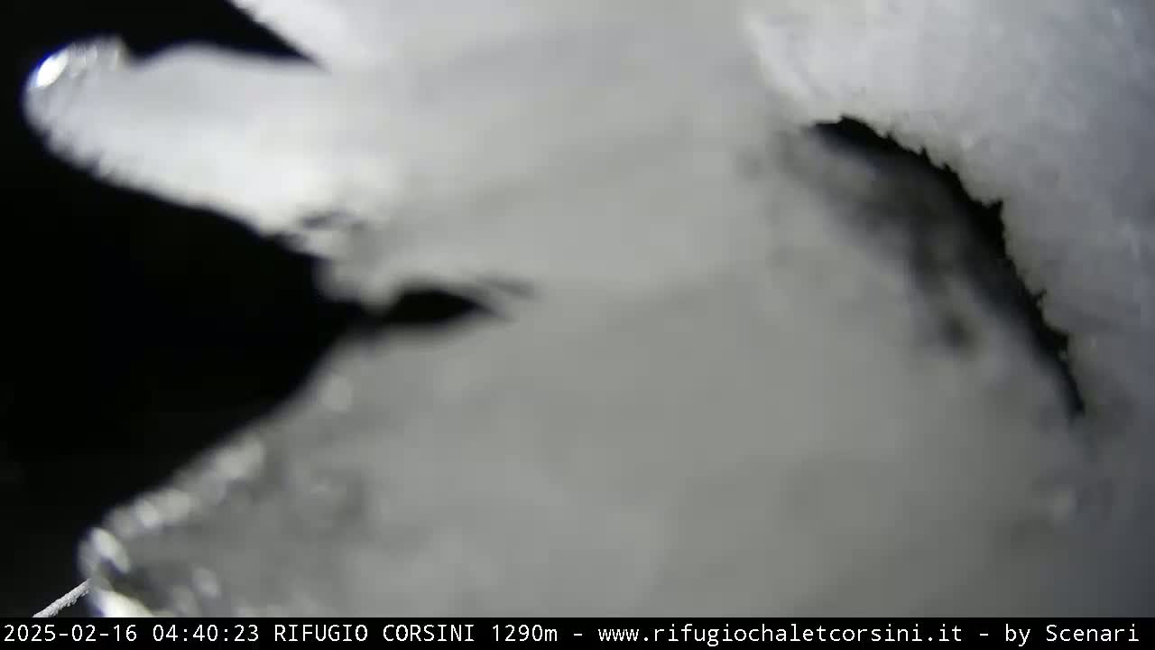 A close-up view shows a mostly white, icy surface with a dark, shadowed crevice running through it.