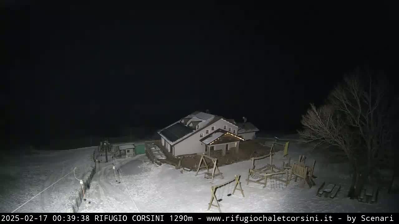 A snow-covered building with a playground sits under a dark night sky.