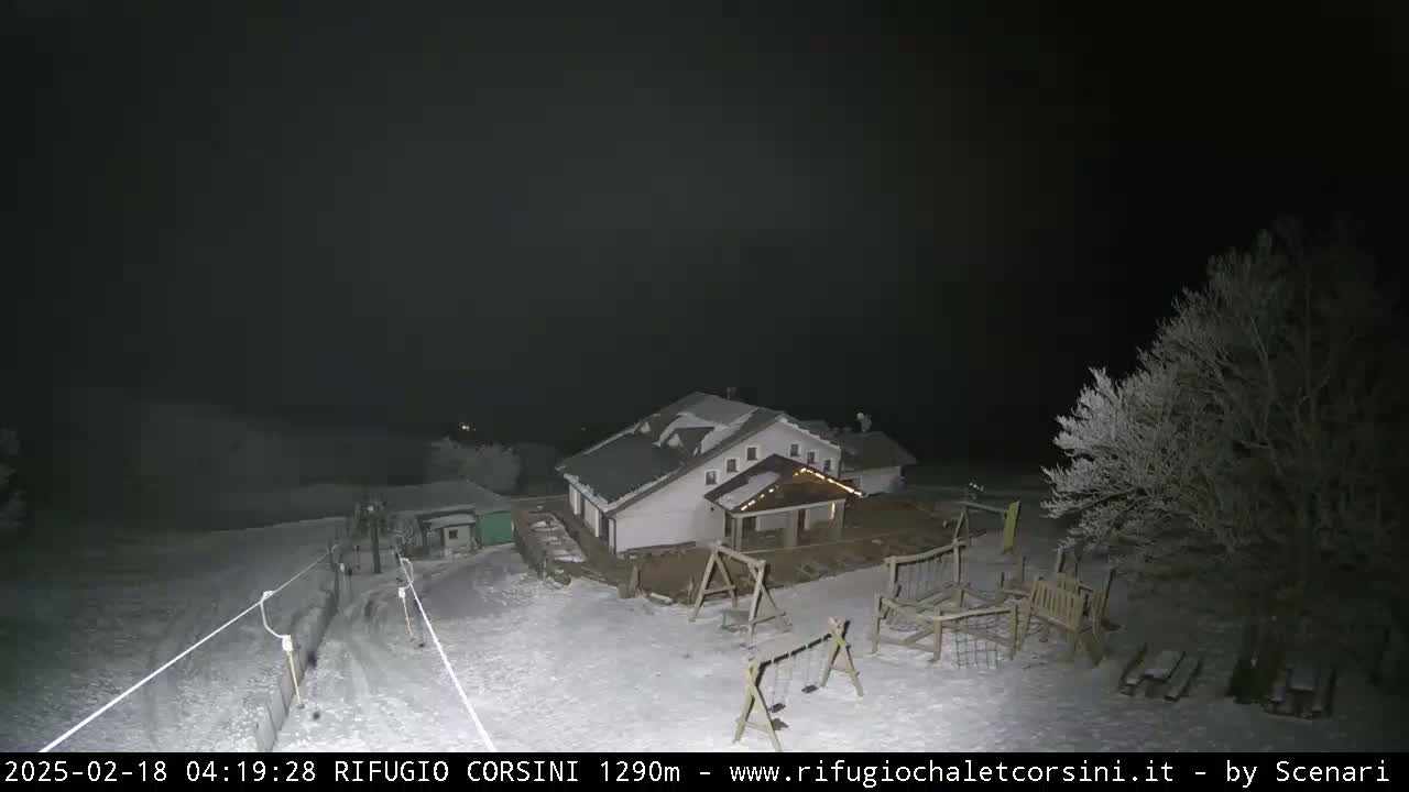 A snow-covered building with a playground is visible at night under a dark sky.