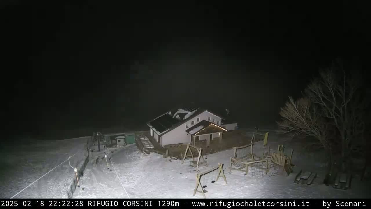 A snow-covered playground and a house are visible at night under a dark, hazy sky.
