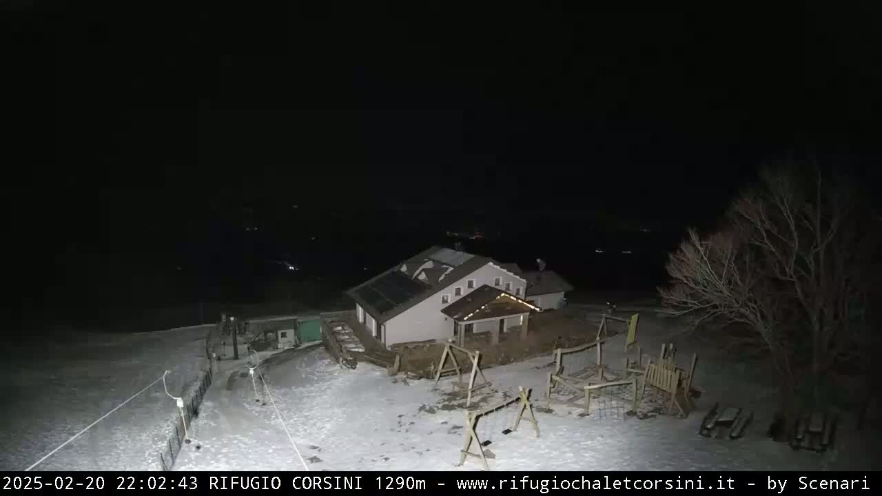A snow-covered playground and building are visible at night under a dark sky.