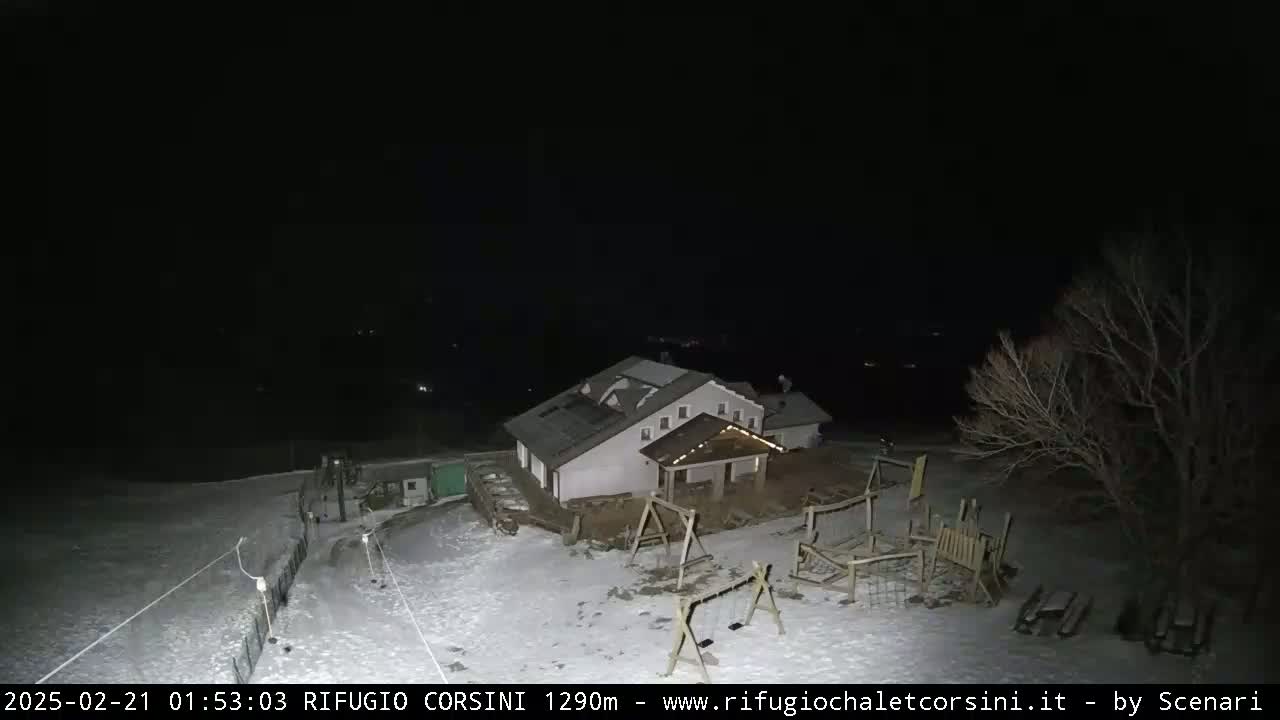 A snow-covered playground and building are visible at night under a dark sky.