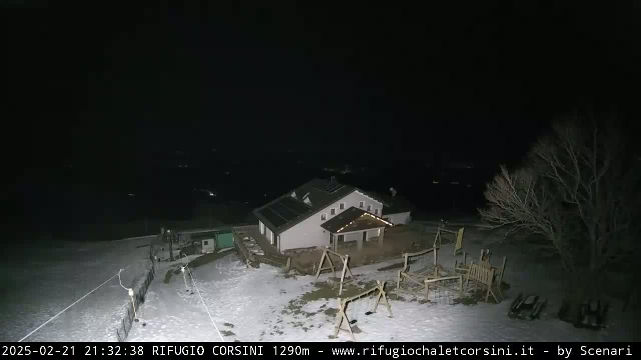 A nighttime view of a snow-covered building with a playground, under a clear, dark sky.