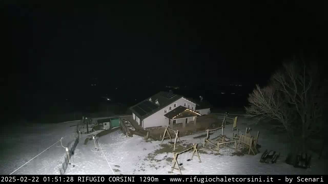 A snow-covered building with a playground is illuminated at night.