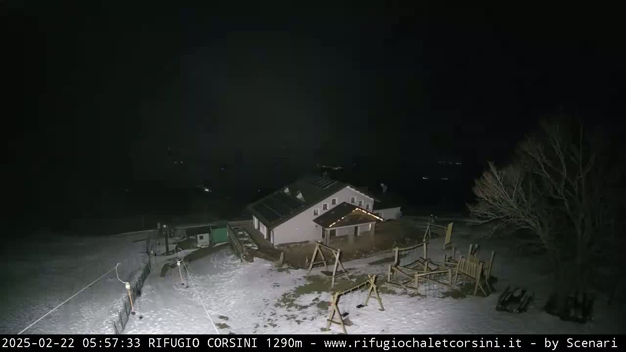 A snow-covered building with a playground is visible at night under a dark sky.