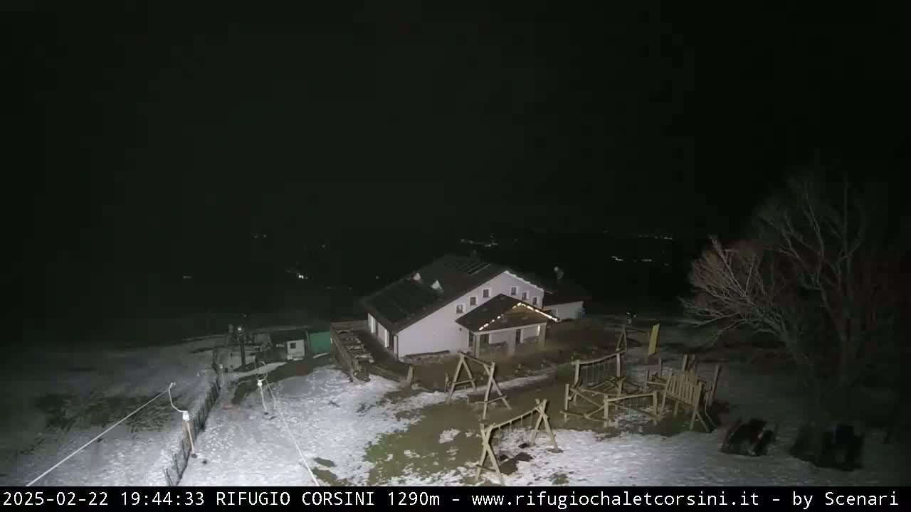 A nighttime view of a building with a playground, partially covered in snow, under a clear, dark sky.