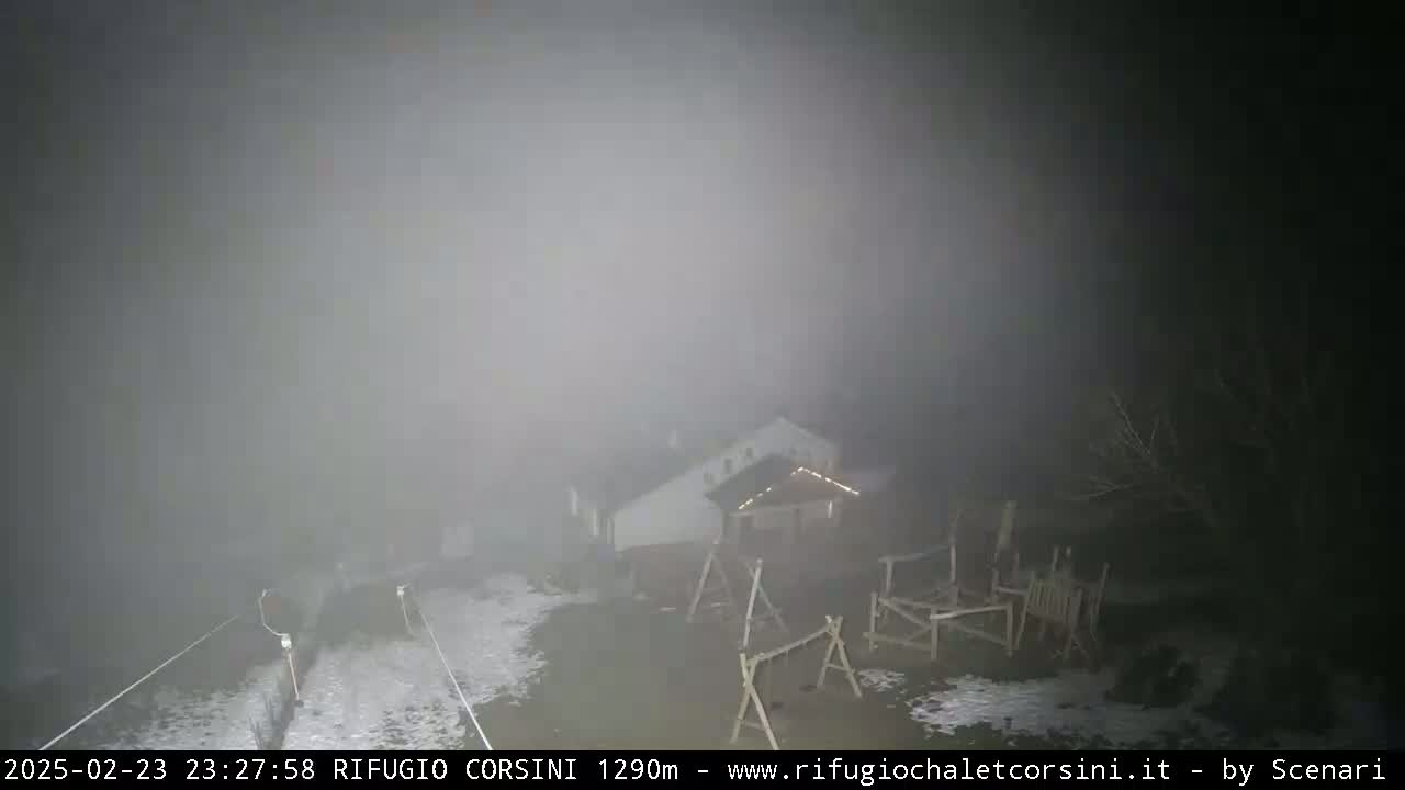 A building and playground are barely visible through heavy fog at night.