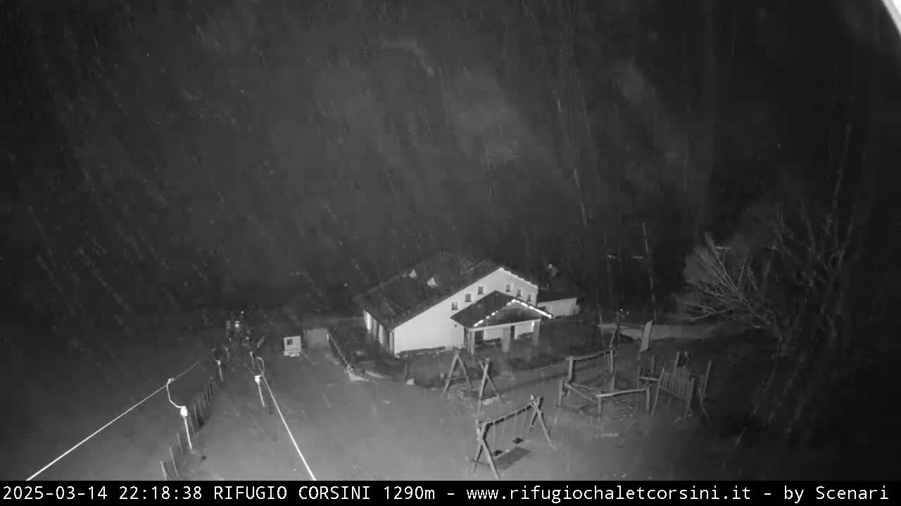 A building with a playground is seen at night under heavy snowfall.