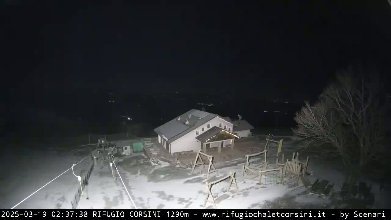 A building with a playground sits in a snow-covered area at night under a dark sky.