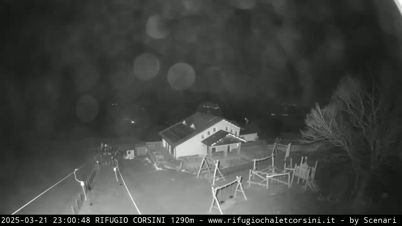 A nighttime, blurry, black and white image shows a building with a playground next to it, under a dark, possibly rainy sky.
