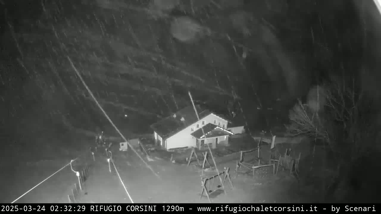 A nighttime, overhead view of a building with a playground, under heavy snowfall.