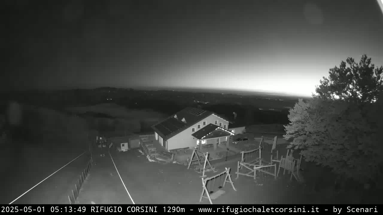 A building with a playground is visible at twilight, overlooking a dark, hilly landscape under a mostly clear sky.