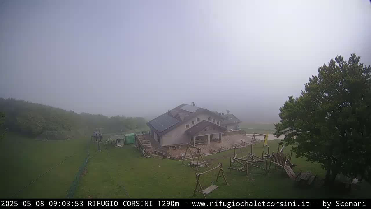 A building with a playground sits on a grassy area in a foggy landscape.