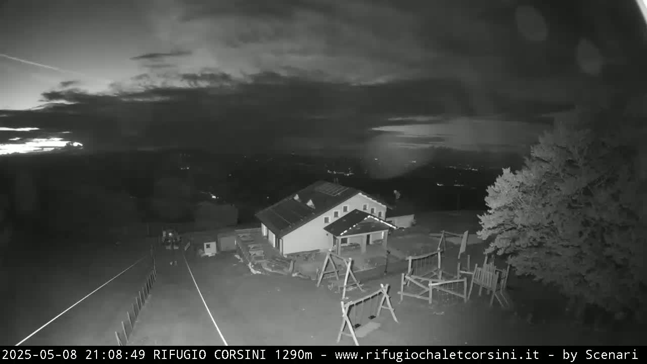 A nighttime, low-light view of a building with a playground, under a partly cloudy sky.