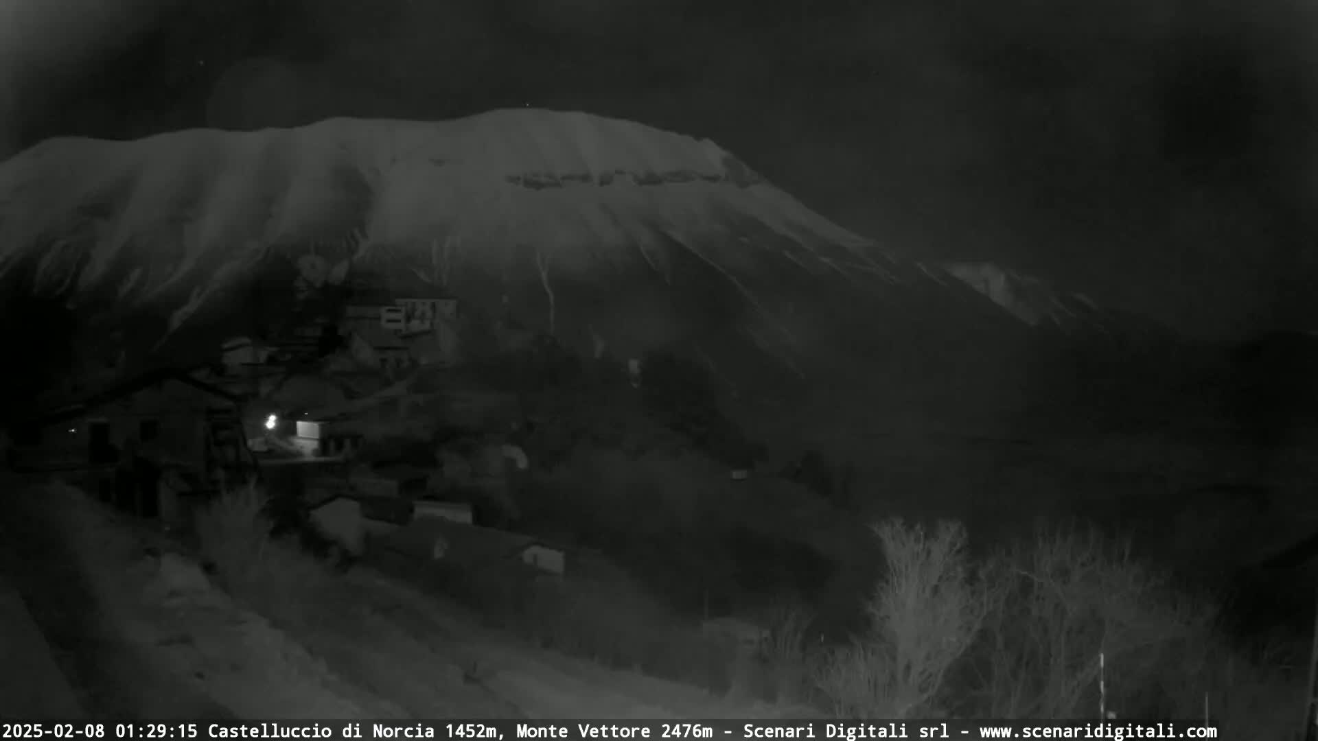 A snow-covered mountain looms over a small village at night.