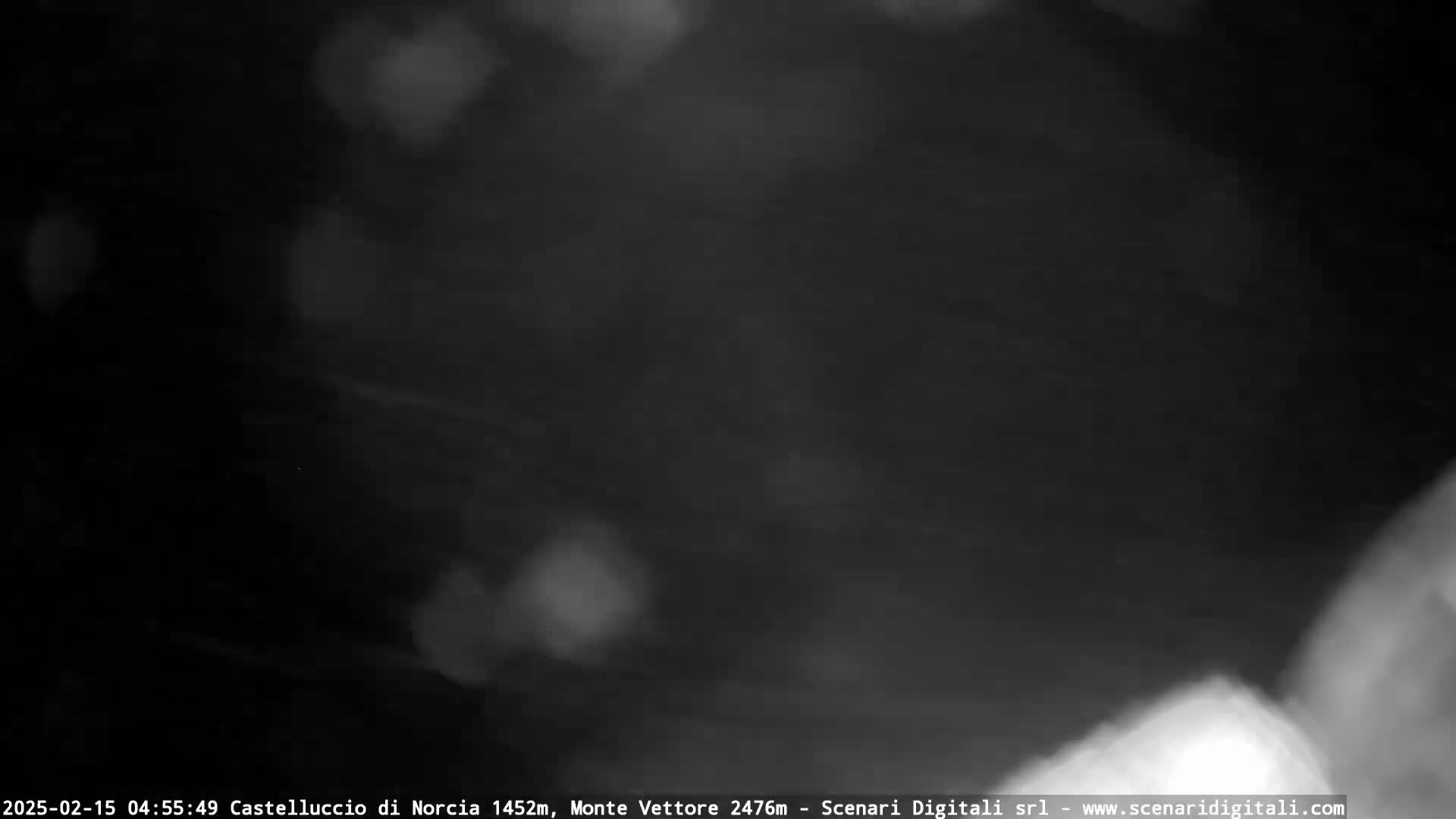 A nighttime, blurry image shows a dark sky with faint, indistinct light sources and what appears to be fog or mist.
