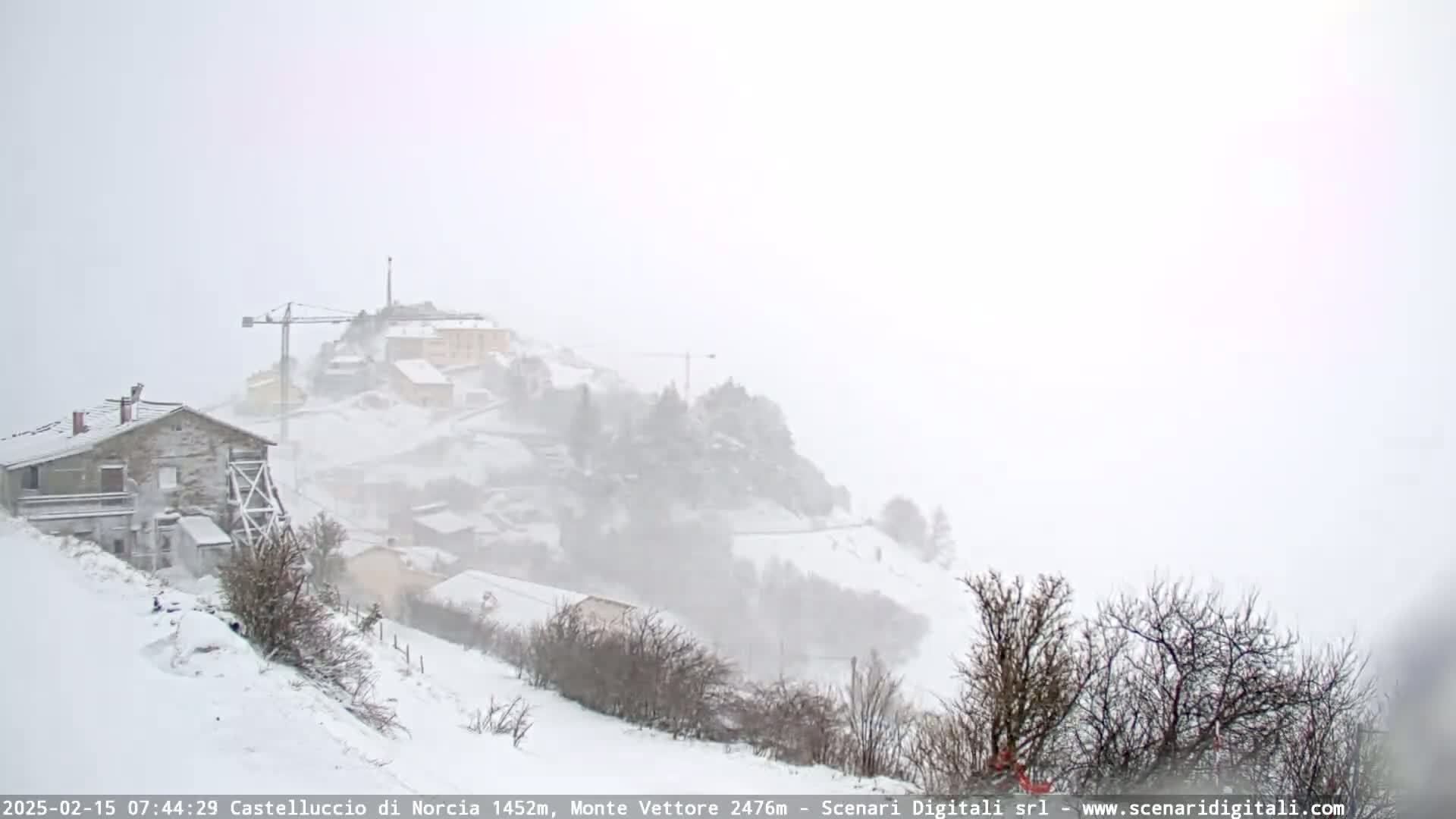 A snow-covered hillside village is seen during a heavy snowstorm.