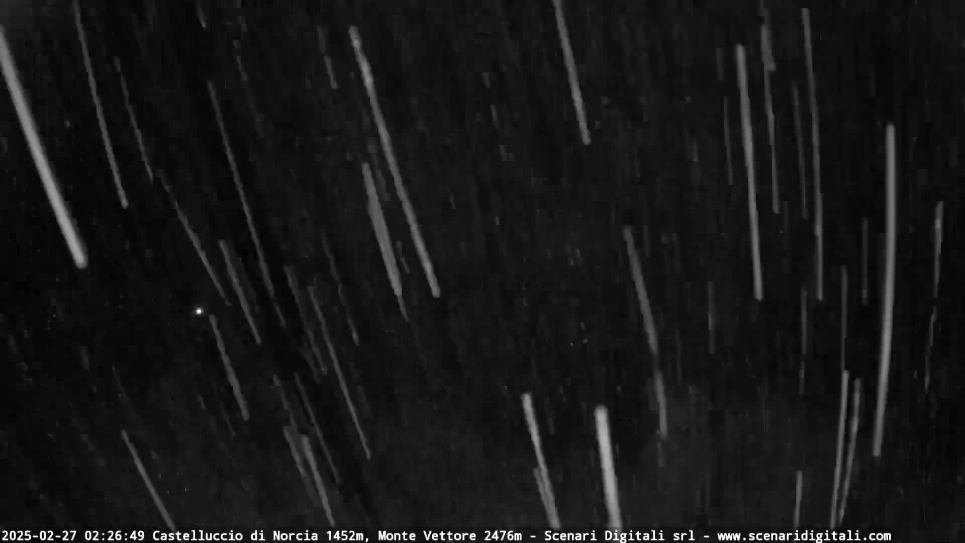 Many streaks of white light fall against a dark, nighttime sky.