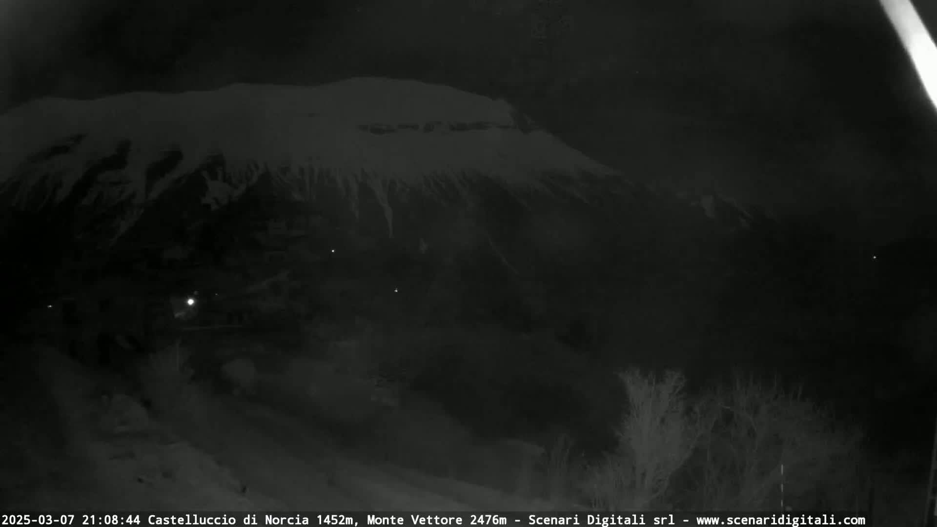 A snow-covered mountain is visible at night under a dark sky.