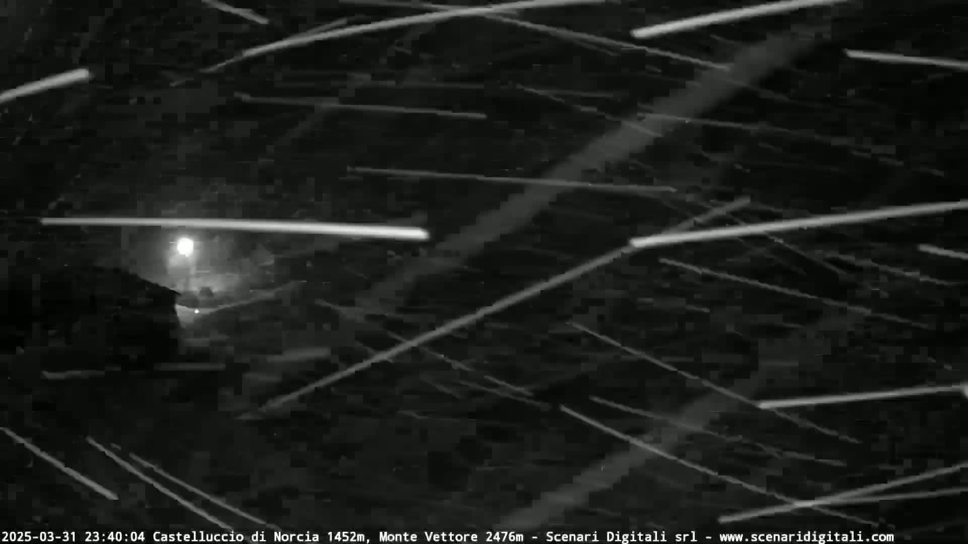 A nighttime scene of heavy snowfall illuminated by a single light source.