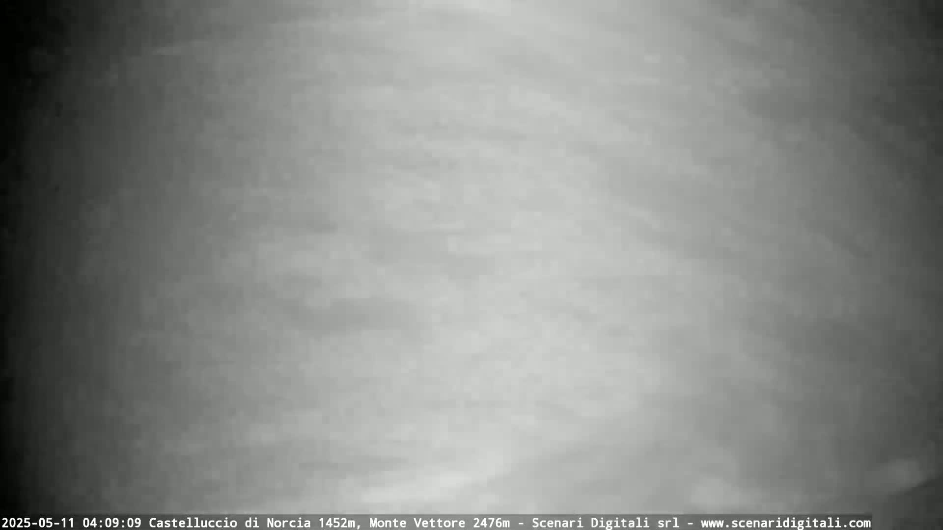 A blurry, grayscale image shows a cloudy, overcast sky.