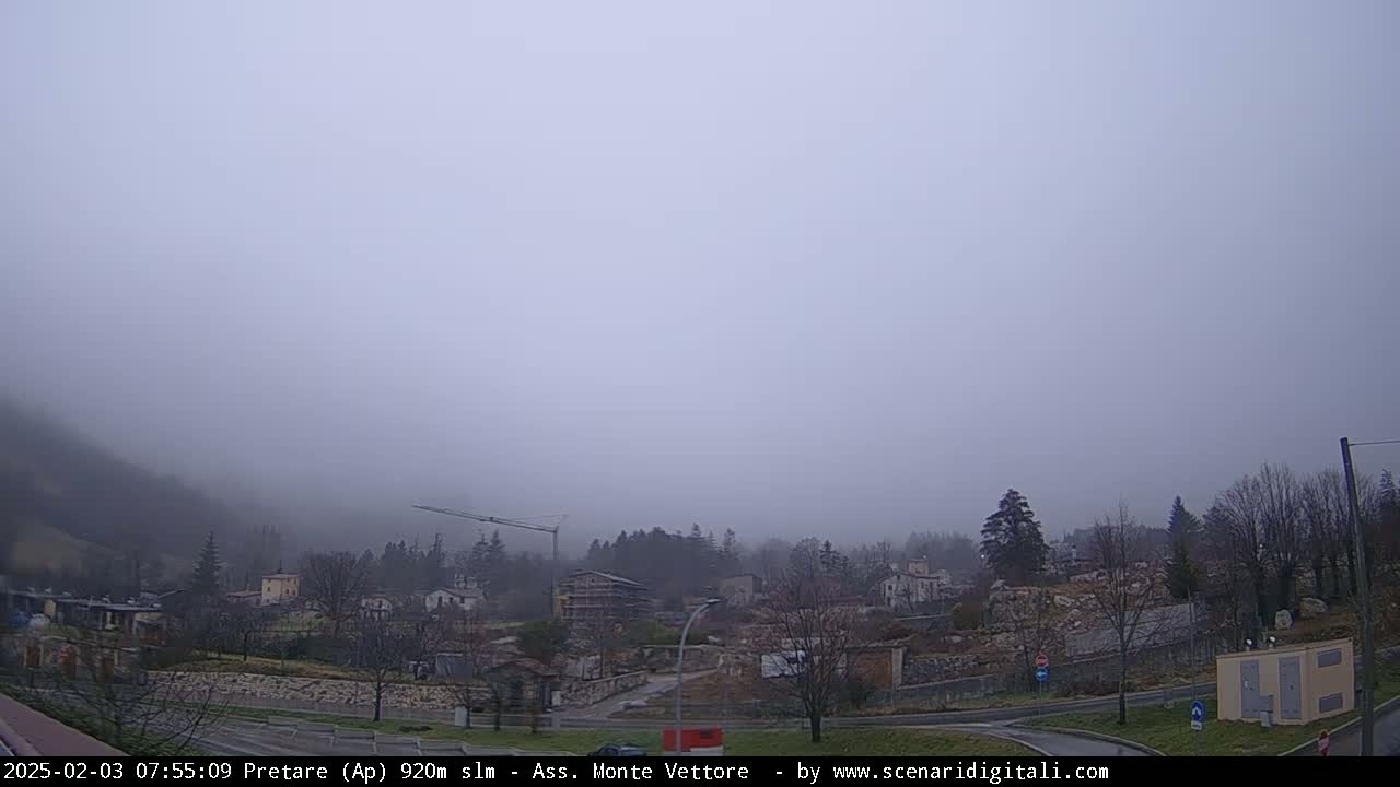 A foggy view of a small town nestled in a valley, with construction visible in the midground.