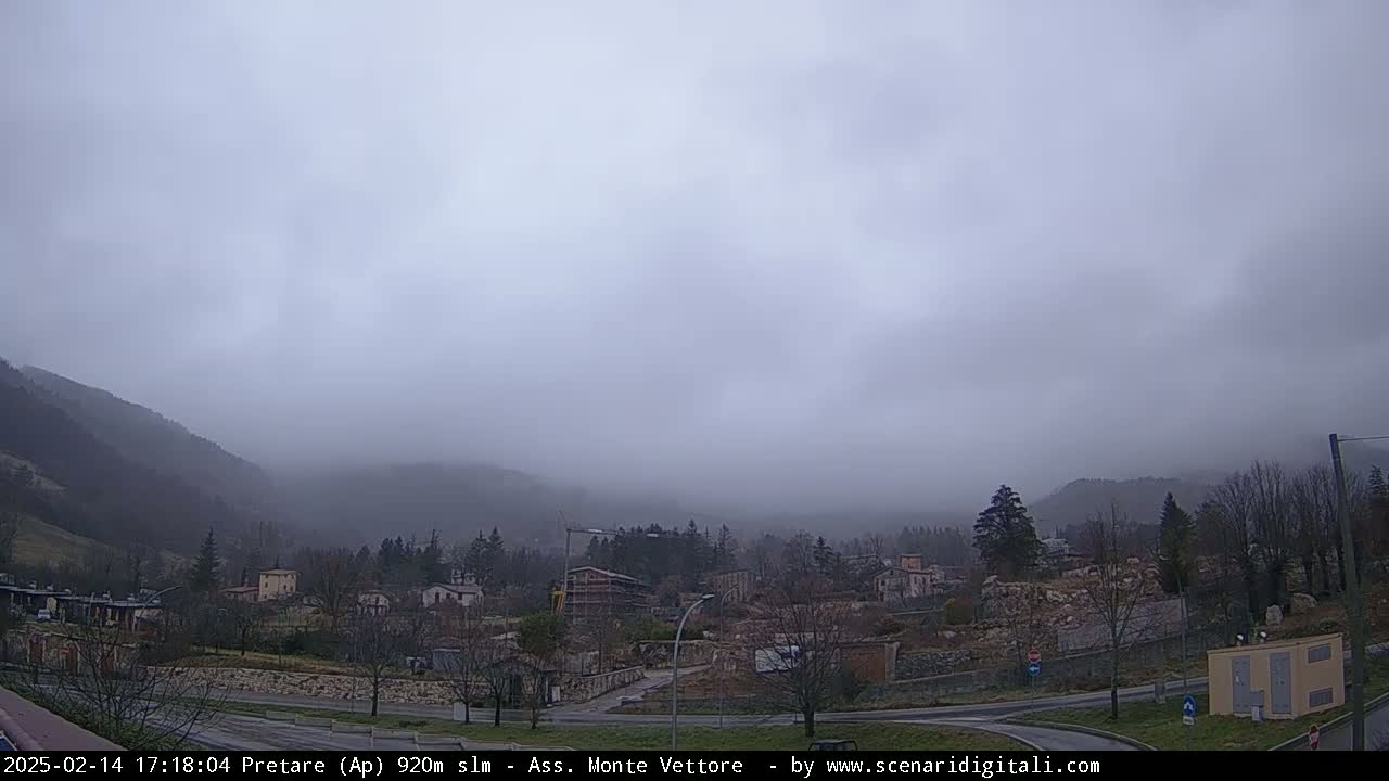 A foggy, overcast day reveals a small town nestled in a valley between mountains.