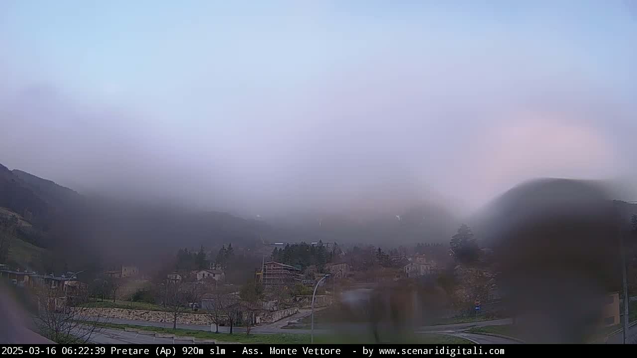 A foggy, overcast view of a small town nestled in a valley between hills.