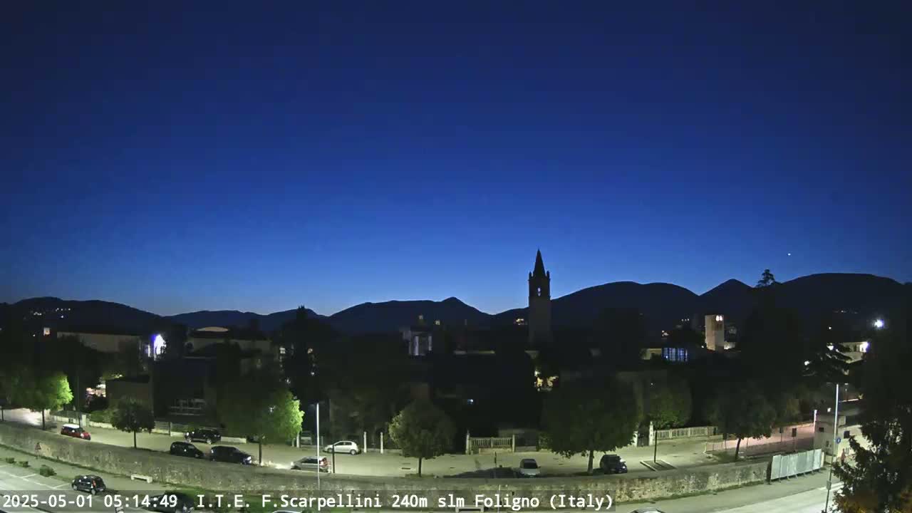 A dark-blue twilight sky over a town nestled against silhouetted mountains.