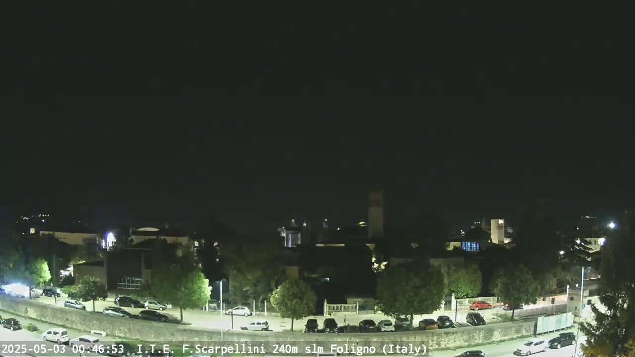 A nighttime, clear-sky view shows a parking lot and buildings in a small town.