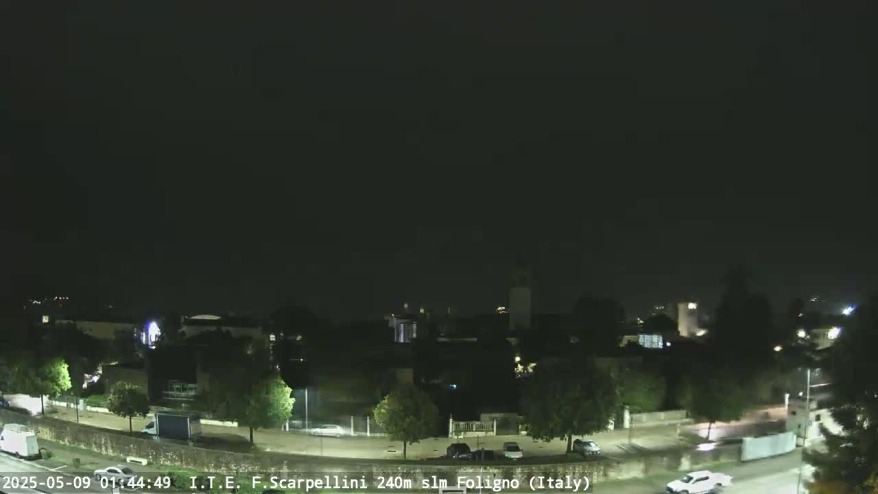 A nighttime view of a town with a few cars on the road under a dark, overcast sky.