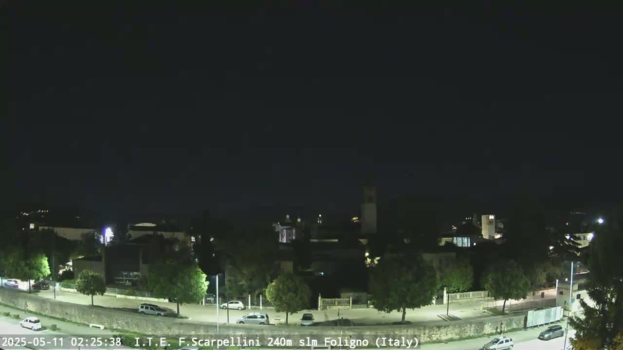 A nighttime view of a town with a few cars on a road, under a clear, dark sky.