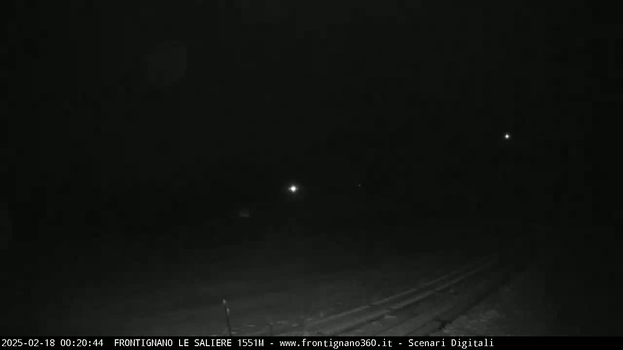 A dark, nighttime road is visible with faint lights in the distance under a clear, dark sky.