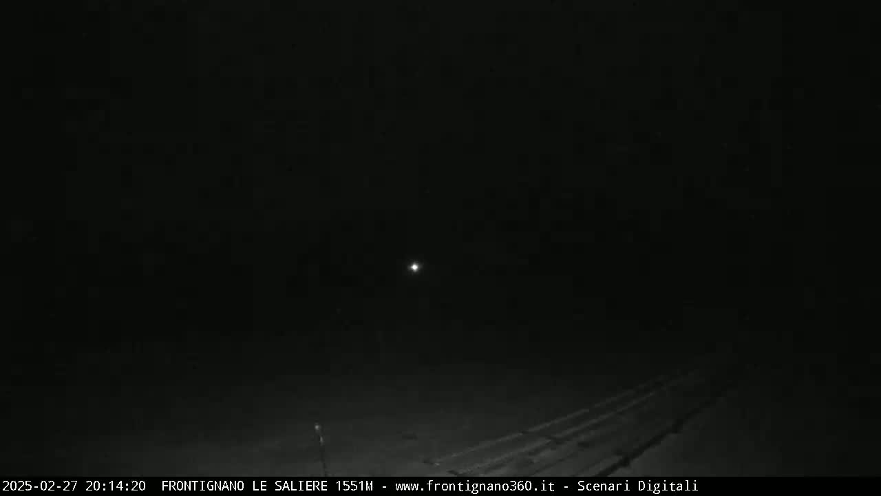 A dark, nighttime outdoor scene shows a faintly lit road and a single distant light source in the sky.