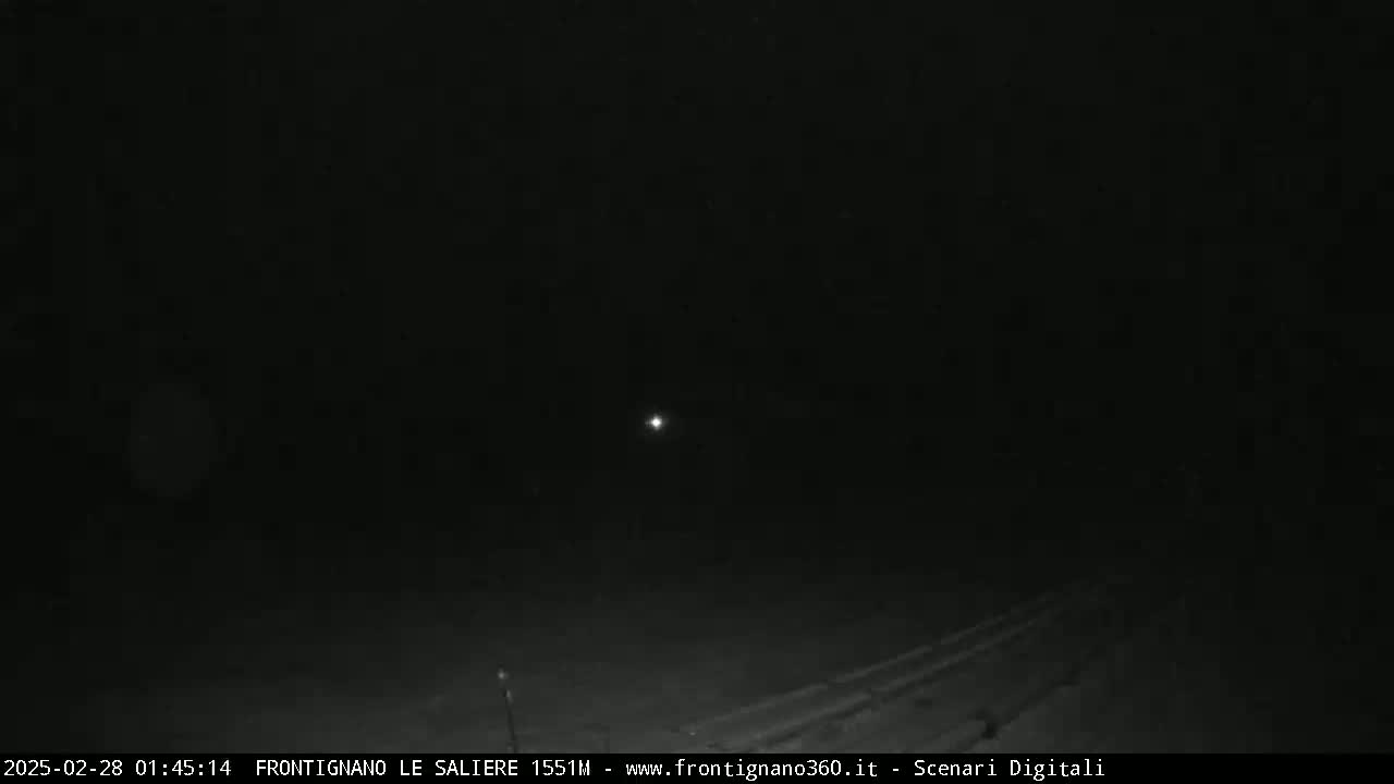 A dark, nighttime scene shows a faintly illuminated road and a single, distant light source in the sky.