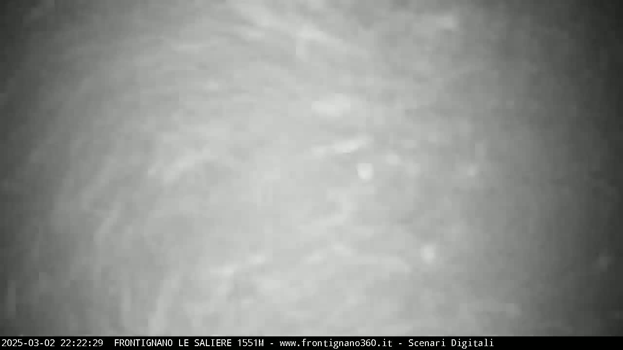 A grainy, black and white image shows a cloudy night sky.