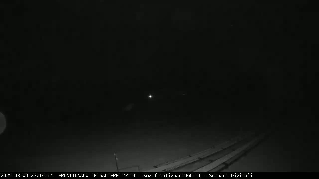 A nighttime, low-light view of what appears to be a roadway or similar paved surface, with faint lights visible in the distance.