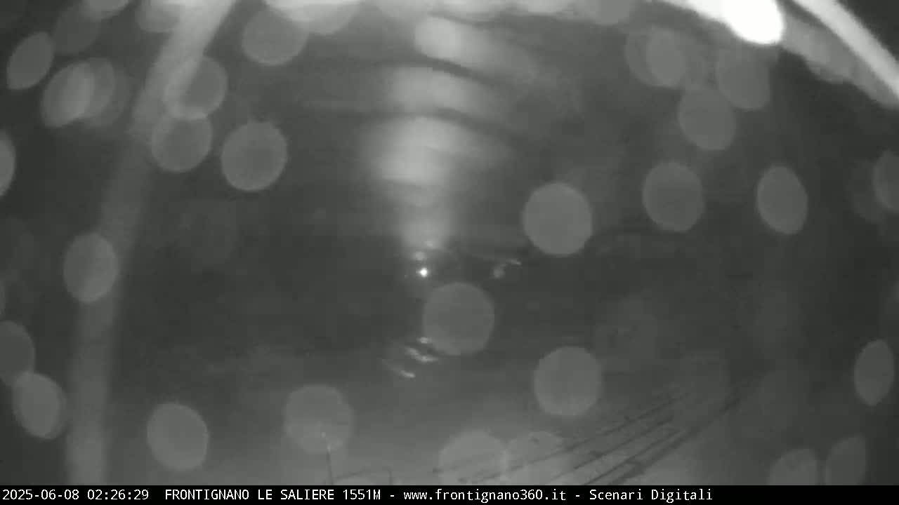 A blurry, nighttime image shows out-of-focus lights resembling raindrops on a dark surface.