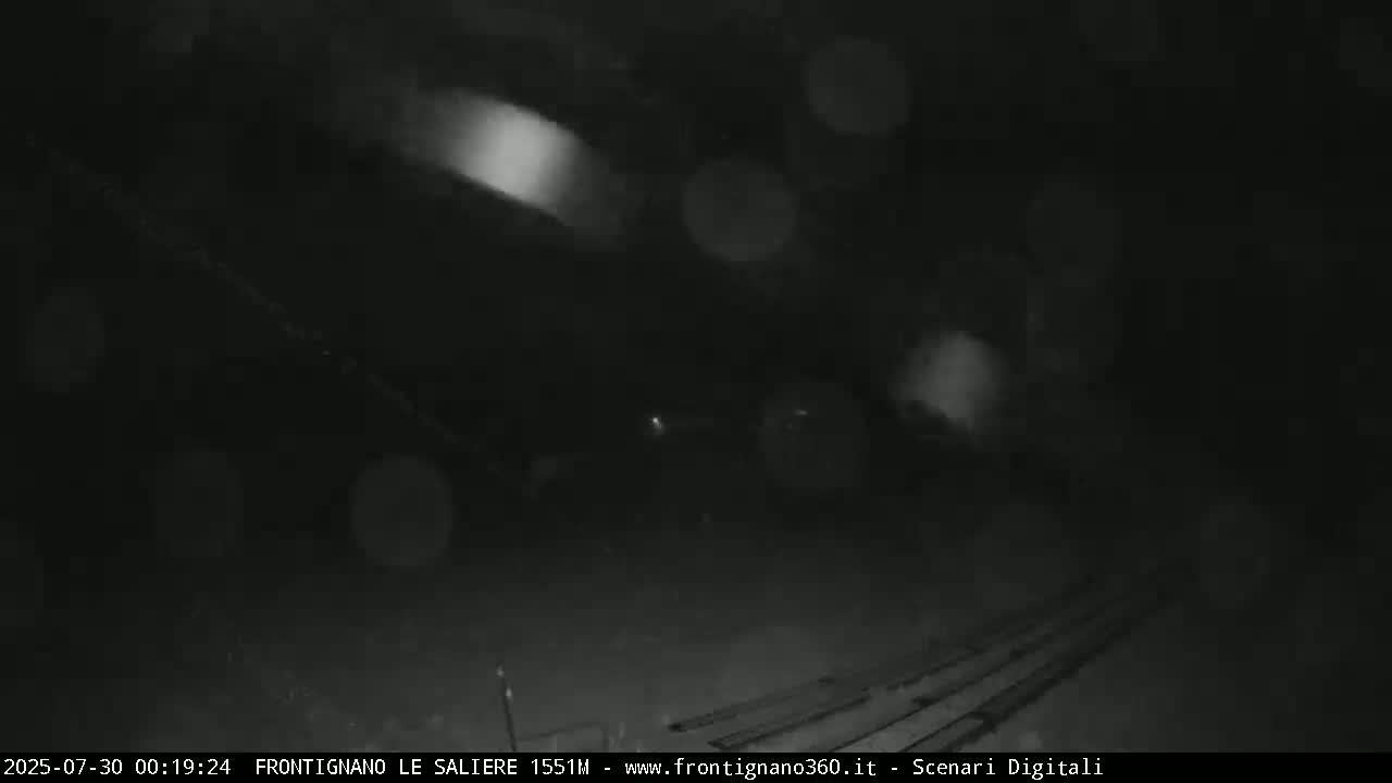 A nighttime outdoor scene shows blurry lights and falling snow or rain.