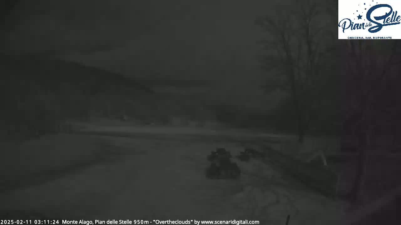 A dark, snowy landscape is visible at night, with two vehicles in the lower center.