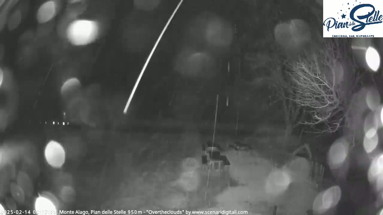 A meteor streaks across a nighttime sky filled with falling snow.