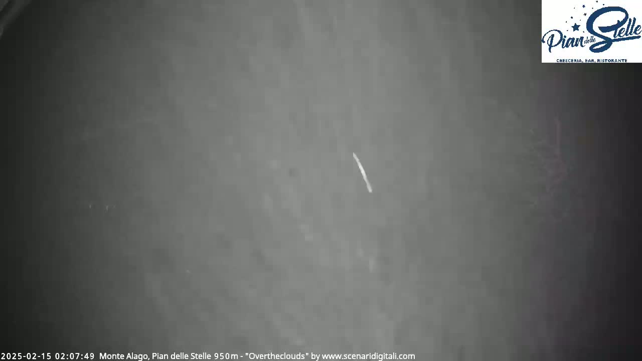 A long, thin, white streak is visible against a dark, overcast night sky.