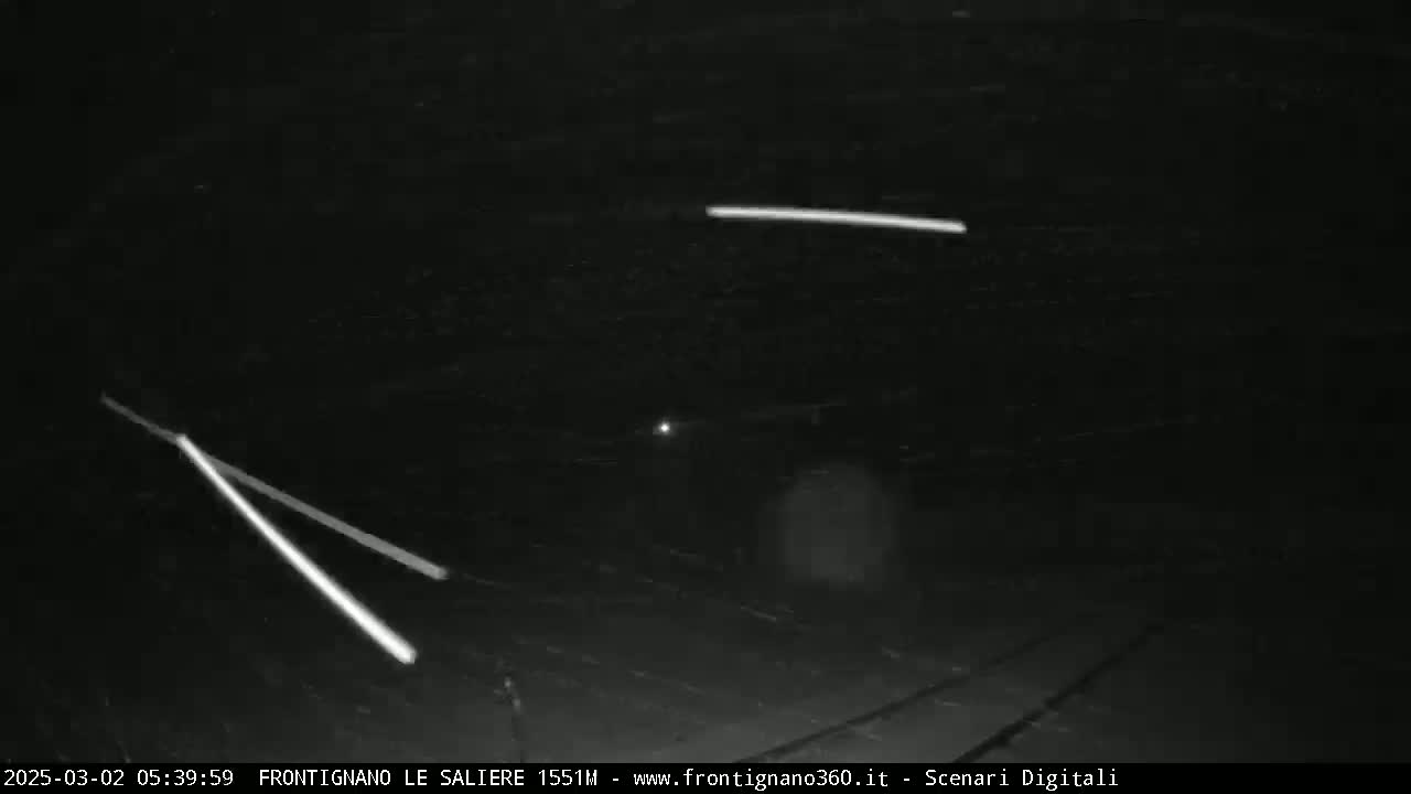 Headlights from two vehicles are visible on a dark road at night.