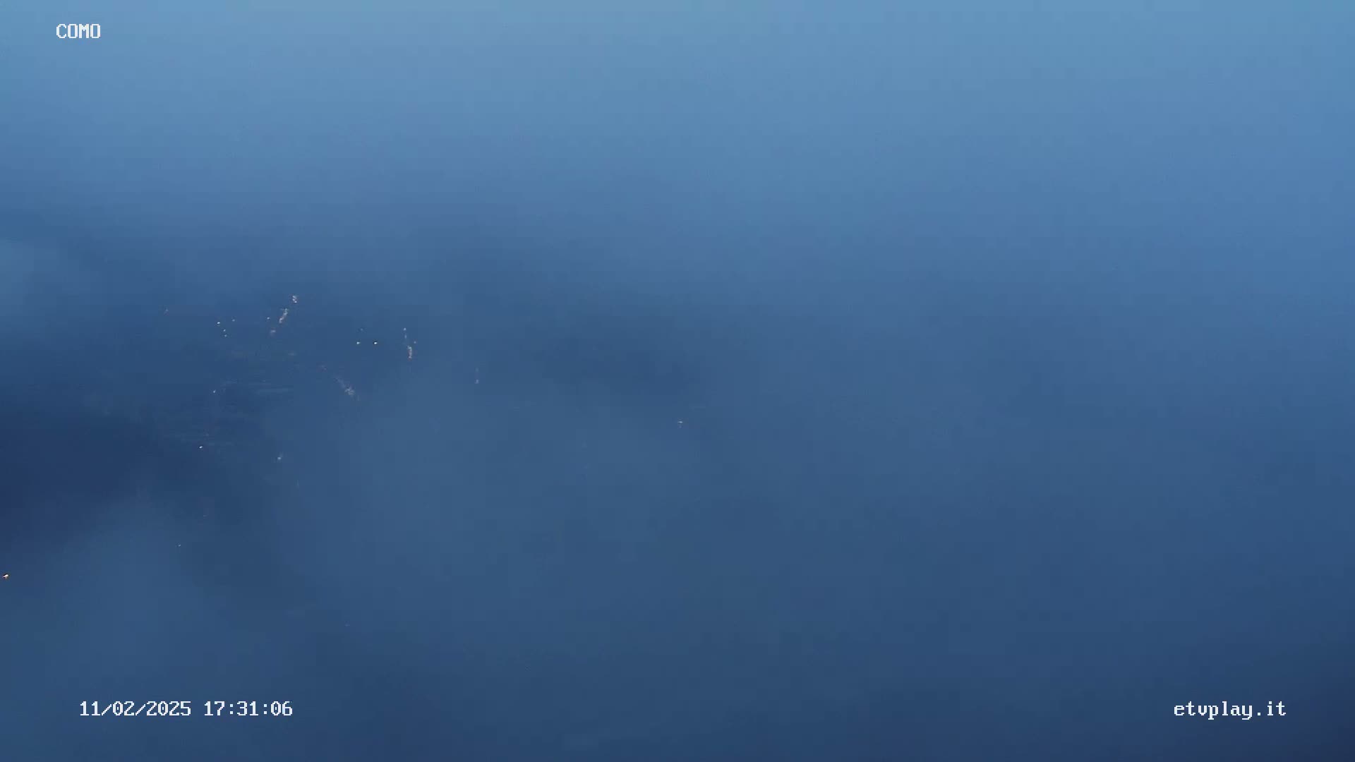 A hazy, bluish-gray fog obscures a distant, dimly lit landscape.