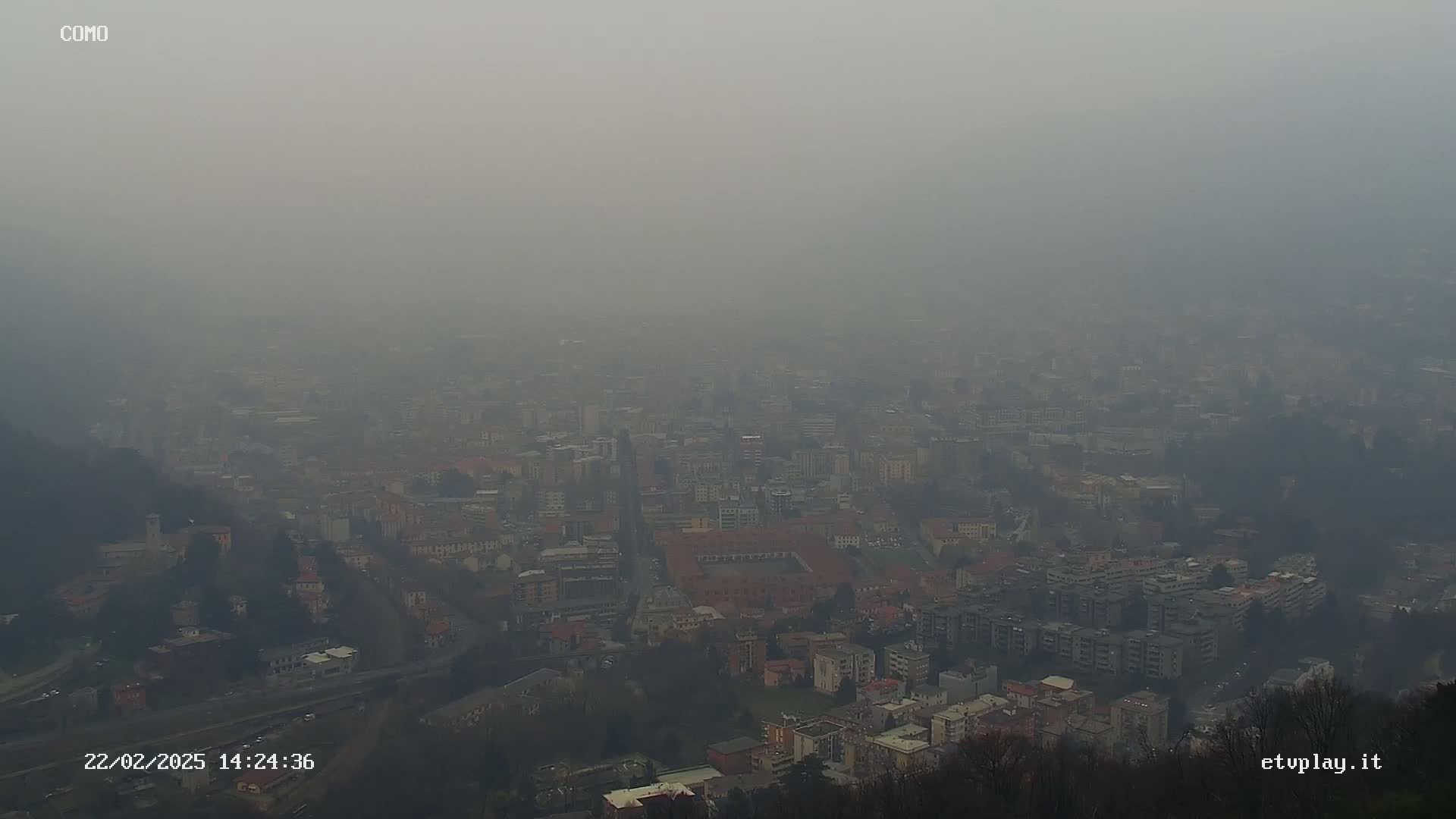 A hazy, gray cityscape is viewed from a high vantage point.