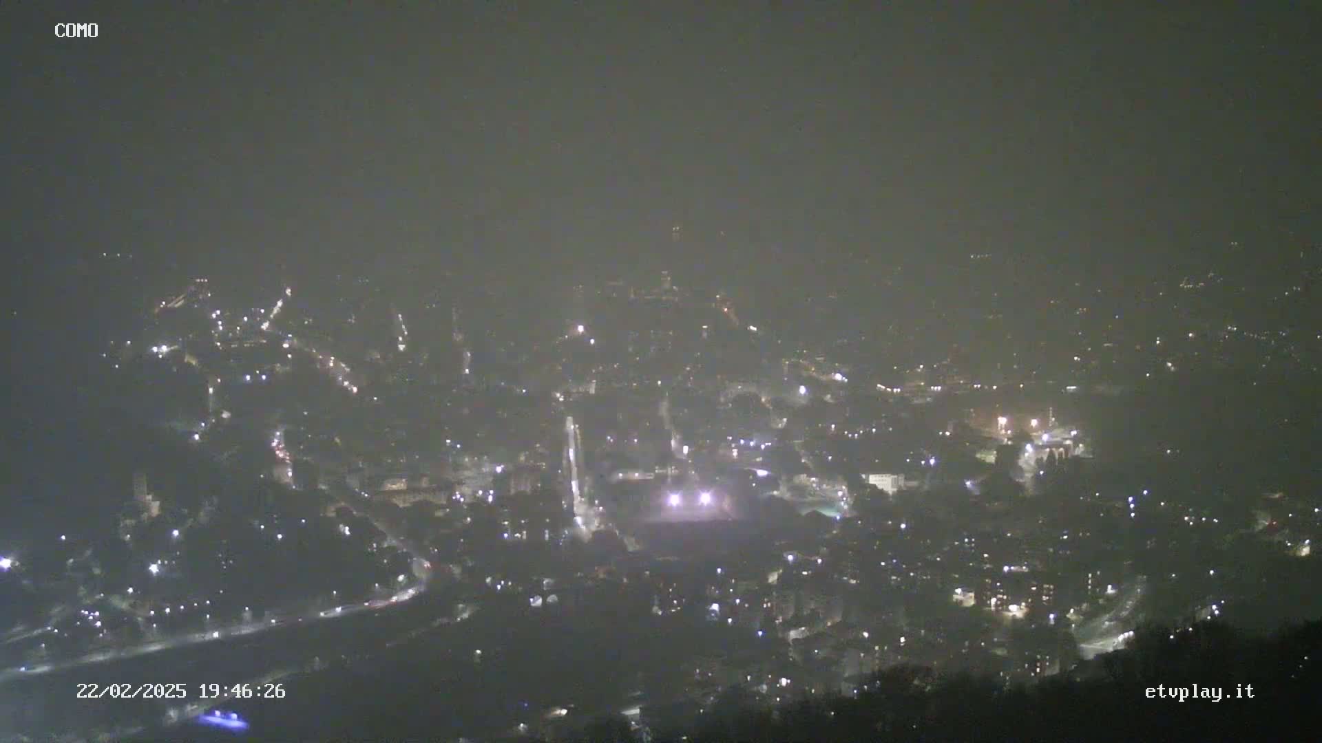A hazy night view shows a city with scattered lights below.