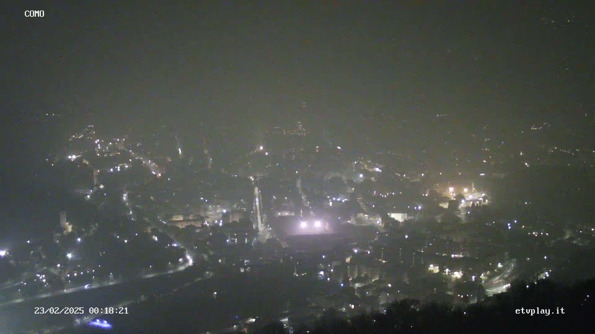 A hazy night view of a city with scattered lights visible through the fog.